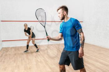 Active couple with rackets play squash game in indoor training club. Recreation workout, match with racquet