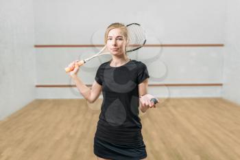 Squash game female player with racket and ball in hands, indoor training club on background