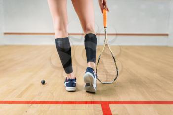 Squash game female player legs, racket and ball, indoor training club on background. Active sport lifestyle