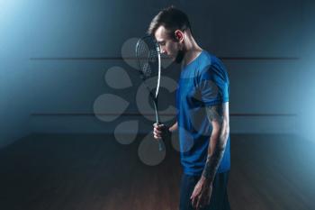 Squash game concept, male player with racket, indoor training court on background