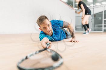 Squash training, male player with racket lies on the floor. Active sport workout. Game with ball and racquet