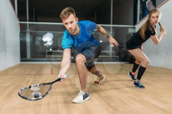 Squash game training, male and female players with rackets. Young couple plays racquets, indoor sport club