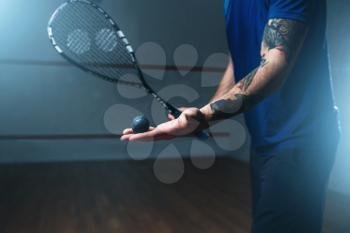 Male squash player with racket training on indoor court. Active sport with racquet and ball