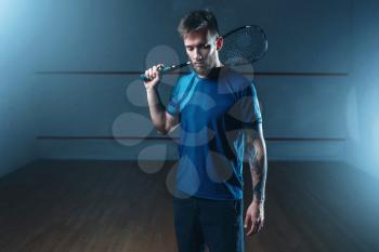 Male squash player with racket, indoor training court on background. Active sport with racquet