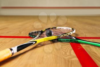 Squash game equipment closeup view. Rackets and ball on the floor in indoor training club