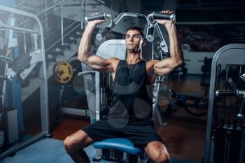 Tanned man training on exercise machine. Active sport workout in gym