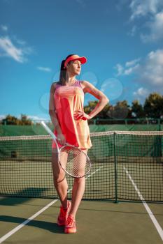 Athletic woman with tennis racket poses on outdoor court. Summer season active sport game