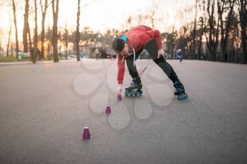 Roller skater in skates, balance exercise on sidewalk in city park. Male rollerskater leisure