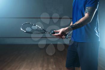 Male squash player with racket training on indoor court. Active sport with racquet and ball