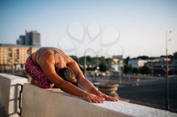 Yoga meditation exercise, woman relax, city on background. Yogi training outdoors