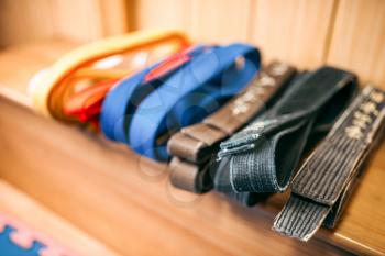 Martial arts, brown, orange, blue and black belts on the shelf closeup, nobody