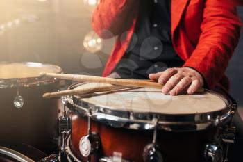 Male drummer in red suit sitting behind the drum set. Musical performer, percussion instrument, live music concert
