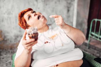 Overweight woman eats sweet cake, laziness and obesity. Unhealthy food eating, fatty female