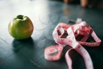 Apple and pink measuring tape on wooden table closeup. Weight loss diet concept, fat or calories burning