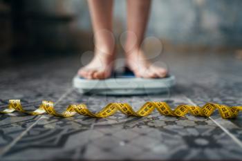 Female feet on the scales, measuring tape. Fat or calories burning concept. Weight loss, hard dieting