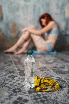 Water and measuring tape against anorexic sick woman, weight loss, anorexia. Fat or calories burning concept, medical illness, nervosa 
