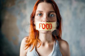 Womans face, mouth sealed with tape labeled food. Fat or calories burning concept. Weight loss, hard dieting, anorexia