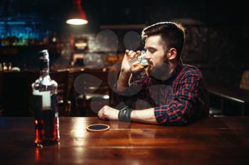 One man sitting at the bar counter and drink strong alcohol beverage. Male person in pub, loneliness