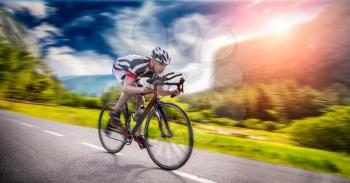 Cyclist in helmet and sportswear rides on bicycle, speed effect, side view. Workout on bike path