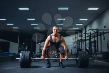 Male powerlifter starting deadlift a barbell in gym. Weightlifting workout, powerlifting training, lifter works with weight in sport club