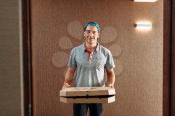 Pizza delivery boy, delivering service. Courier from pizzeria holds cardboard package, takeaway deliver