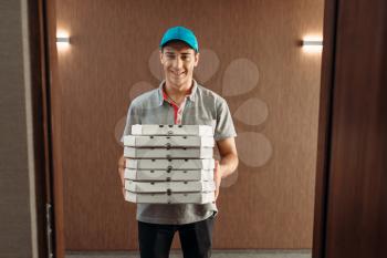 Pizza delivery man with boxes, delivering service. Courier from pizzeria holds cardboard package indoors