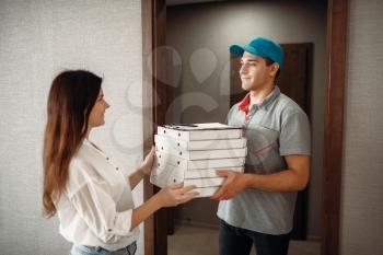 Female customer takes order from pizza delivery boy, fast delivering service. Courier from pizzeria carrying carton boxes and woman at the door