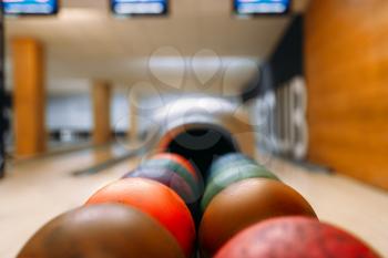 Color bowling balls in feeder, lane with pins on background, nobody. Bowling game concept