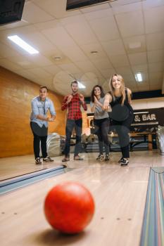 Female bowler throwing, view on rolling ball, strike shot in action. Bowling alley teams playing the game in club, active leisure