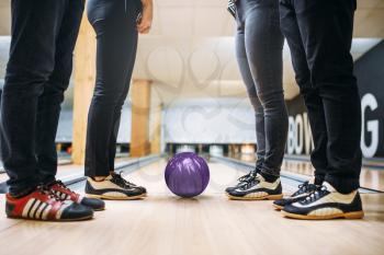 Bowling alley team, feet of the players in house shoes and ball on lane. Friends playing the game in club, active leisure