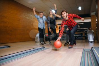 Male bowler throws ball on lane, strike shot. Bowling alley teams playing the game in club, active leisure