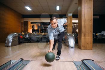 Male bowler throws ball on lane, front view. Bowling alley player, throwing in action, classical tenpin game in club, active leisure
