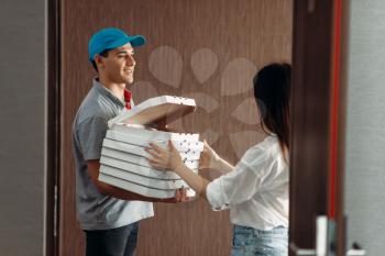 Delivery boy shows fresh and hot pizza to female customer on the doorstep, delivering service. Deliver from pizzeria and woman indoors