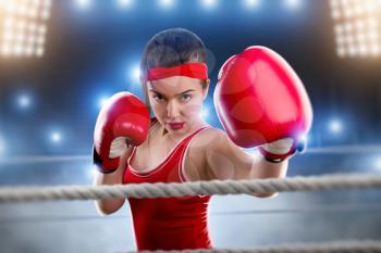 Female boxer in red boxing gloves and sportswear on the ring. Fighting sport concept