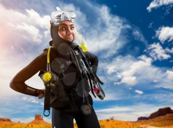 Female diver in wetsuit and diving gear poses on the beach. Frogman in mask and scuba on the beach, underwater sport