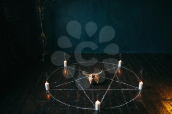 Pentagram circle with candles on black wooden floor. Dark magic ritual with occult and esoteric symbols