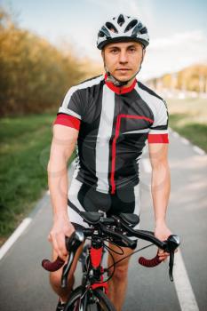 Cyclist in helmet and sportswear on bicycle training. Workout on bike path, cycling