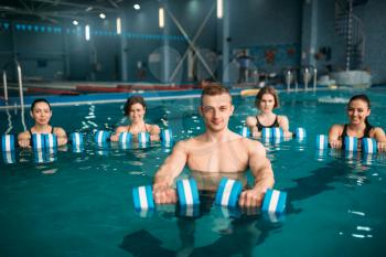Female aqua aerobics group and male trainer doing exercise with dumbbells on training in swimming pool. Fitness workout, water sport 