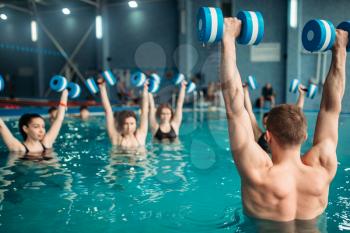 Female class with trainer on workout with aqua dumbbells in swimming pool. Women in swimwear on training, water sport 