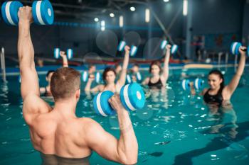 Female class with trainer on workout with aqua dumbbells in swimming pool. Women in swimwear on training. water sport