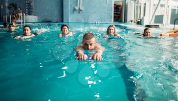 Male trainer swims with female aqua aerobics group on workout in swimming pool. Water sport