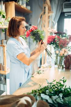 Female florist holds fresh red roses flower shop. Floristry business, bouquet making 