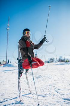Skier in helmet and glasses posing on skis stuck with noses in the snow. Winter active sport, extreme lifestyle. Downhill skiing
