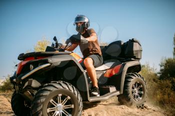 Atv rider in helmet rides on sandy road in forest. Riding on quad bike, extreme sport and travelling, quadbike adventure
