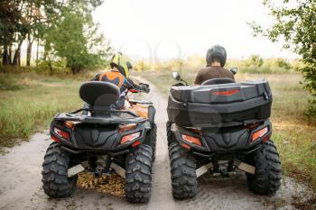 Two atv riders in helmets, back view. Freeriding on quad bike, extreme sport and travelling, quadbike summer adventure