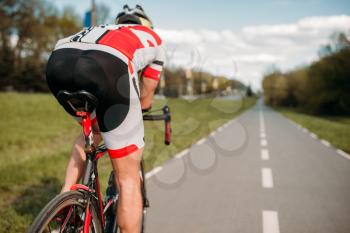 Male cyclist on bike path, view from the rear wheel. Cycling on asphalt road. Sportsman rides on bicycle, bycyclist on workout