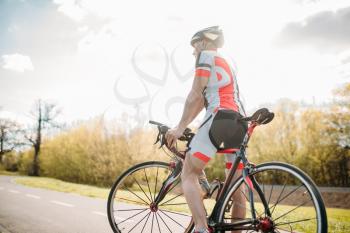Bycyclist in helmet and sportswear on bike workout. Cycling on bike path, training on asphalt road