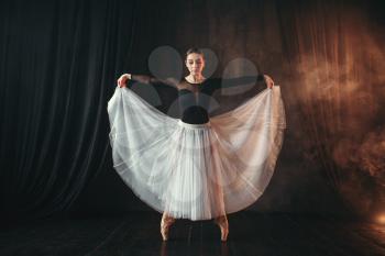 Classical ballet dancer in motion on the stage in theatre. Graceful ballerina poses in studio