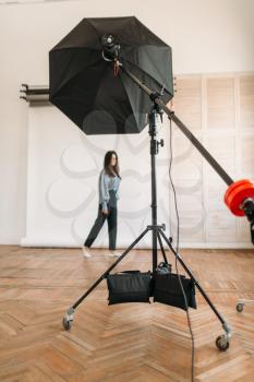 Beautiful model poses in photo studio, white background, lighting equipment. Attractive woman on photo studio shot