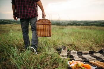 Male person with basket, picnic in summer field. Romantic junket, happy weekend